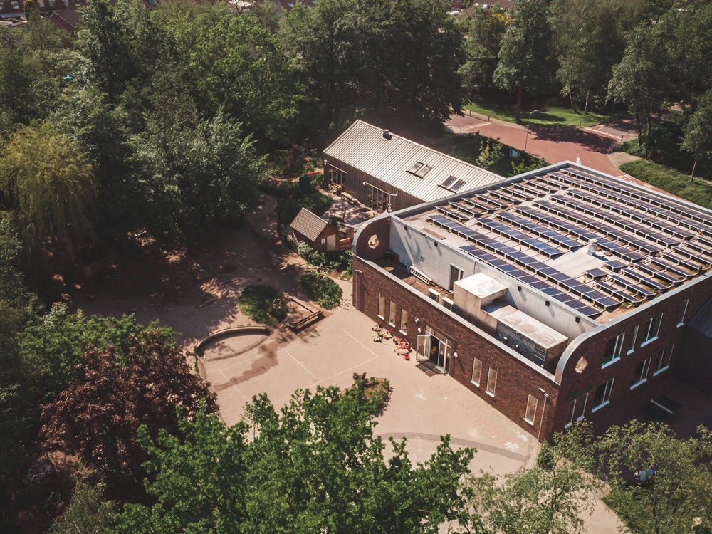 Clădire de școală cu panouri fotovoltaice pe acoperiș, văzută de sus